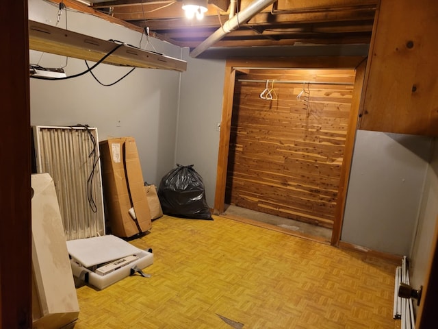 basement with wood walls and light parquet floors