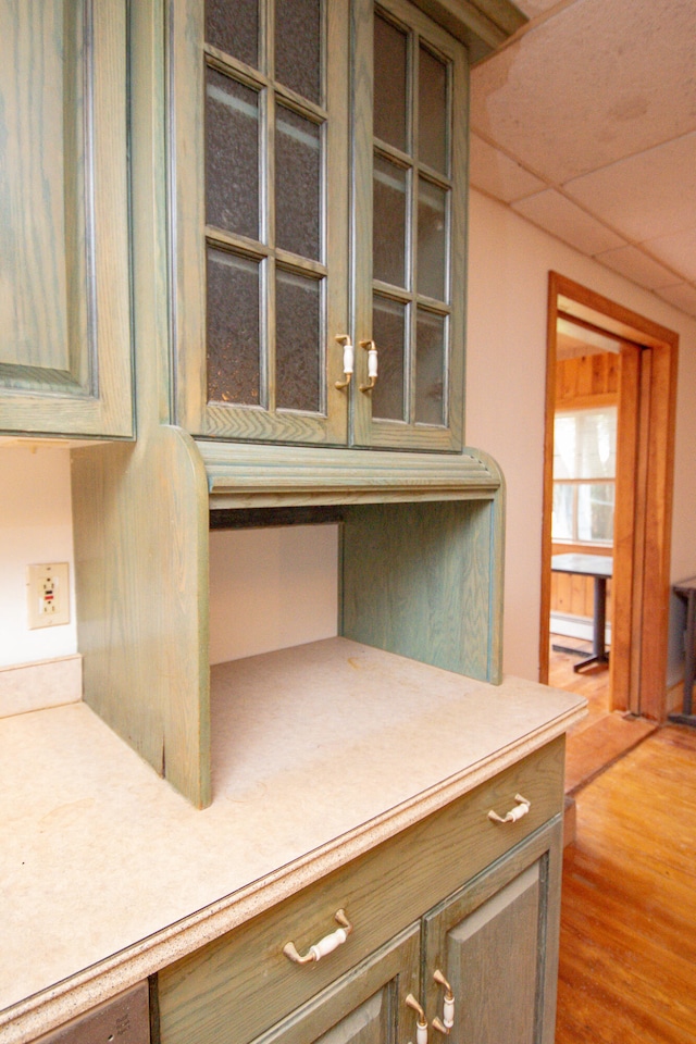 details featuring a drop ceiling, built in desk, and wood-type flooring