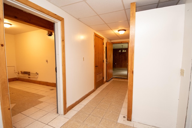 hall featuring a drop ceiling and light tile patterned floors