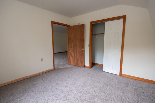 unfurnished bedroom featuring lofted ceiling, a closet, and carpet flooring