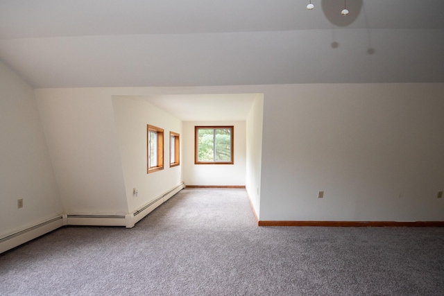 carpeted empty room with a baseboard radiator and vaulted ceiling