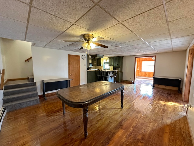 dining room with a paneled ceiling, wood-type flooring, and ceiling fan