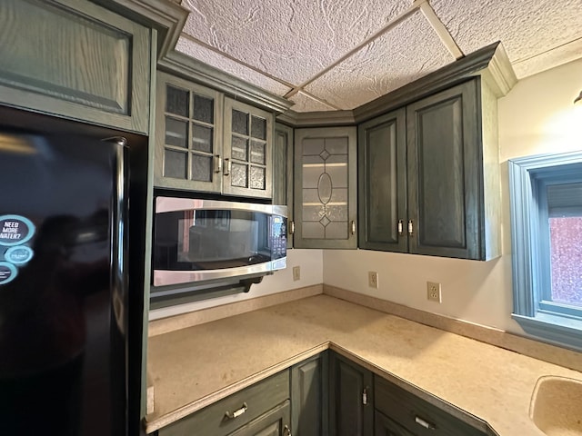 kitchen featuring black fridge and dark brown cabinets