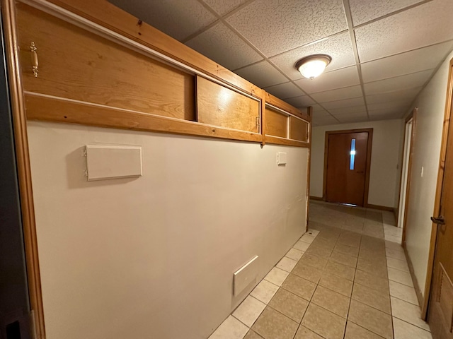 hall featuring light tile patterned flooring and a drop ceiling