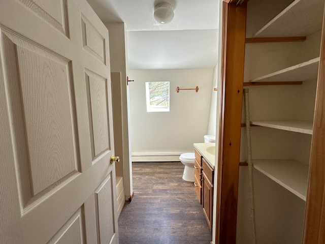 bathroom with hardwood / wood-style flooring, a baseboard heating unit, vanity, and toilet