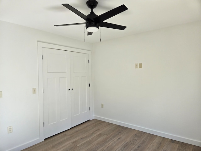 unfurnished bedroom with a closet, wood-type flooring, and ceiling fan