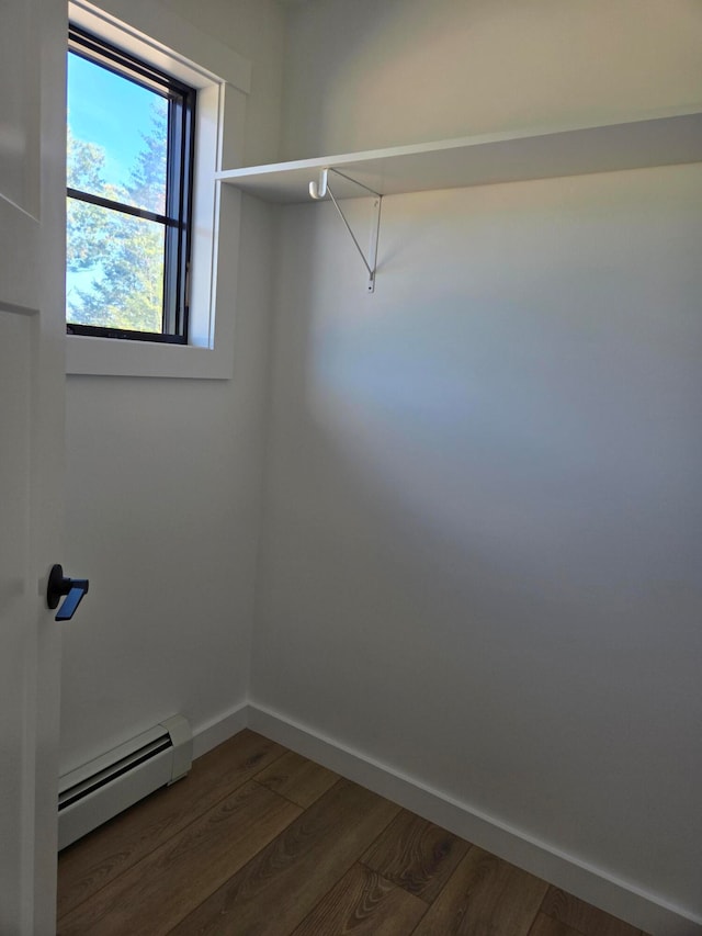 spacious closet featuring a baseboard radiator and dark hardwood / wood-style flooring