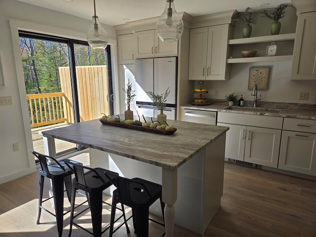 kitchen with white refrigerator, hanging light fixtures, sink, hardwood / wood-style floors, and stainless steel dishwasher