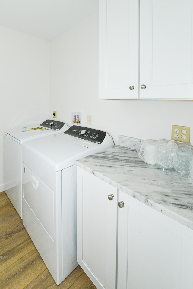 washroom with washing machine and dryer, cabinets, and hardwood / wood-style floors