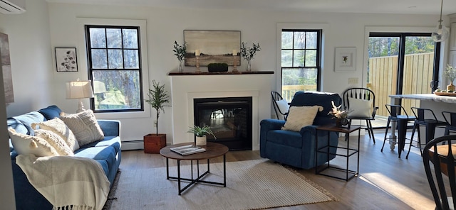 living room featuring a wall mounted AC, a baseboard heating unit, and hardwood / wood-style flooring