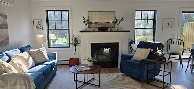 living room with hardwood / wood-style flooring, plenty of natural light, and a baseboard heating unit