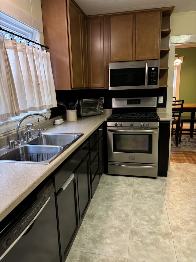 kitchen with appliances with stainless steel finishes, light hardwood / wood-style floors, and sink