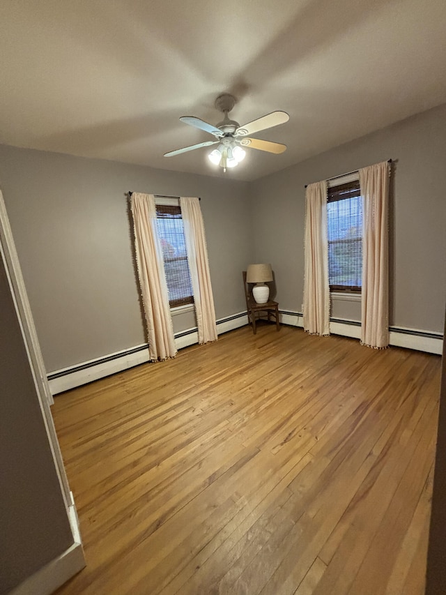 spare room with ceiling fan, a baseboard radiator, and light hardwood / wood-style floors