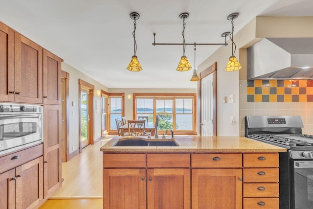 kitchen featuring sink, tasteful backsplash, decorative light fixtures, stainless steel appliances, and light hardwood / wood-style floors