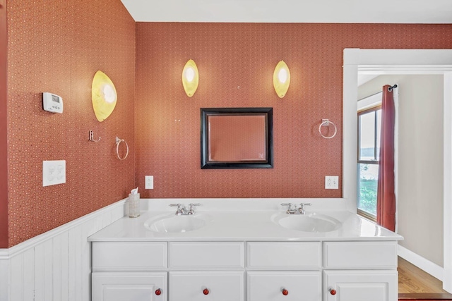 65 Grange Hall Rd, Sullivan, ME 04664 - bathroom featuring wallpapered walls, double vanity, a sink, and wood finished floors
