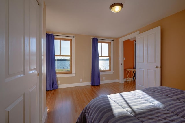 bedroom with light wood-type flooring and a water view