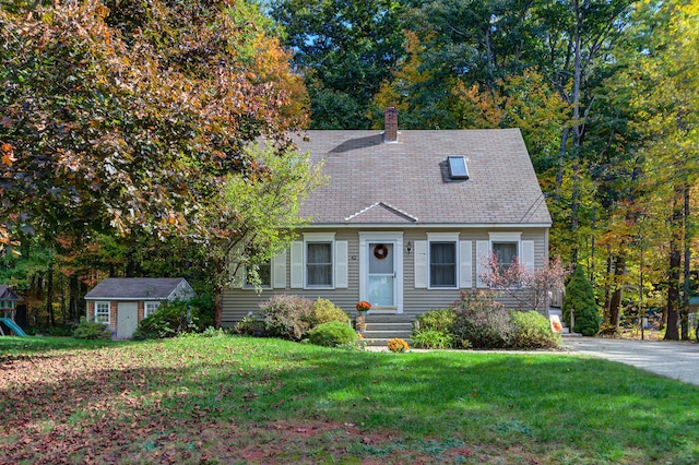 cape cod house featuring a front yard and a storage unit