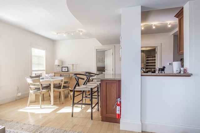 kitchen with rail lighting, light hardwood / wood-style floors, light stone countertops, and kitchen peninsula