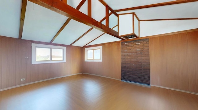 unfurnished room with wood walls, lofted ceiling with beams, and hardwood / wood-style floors