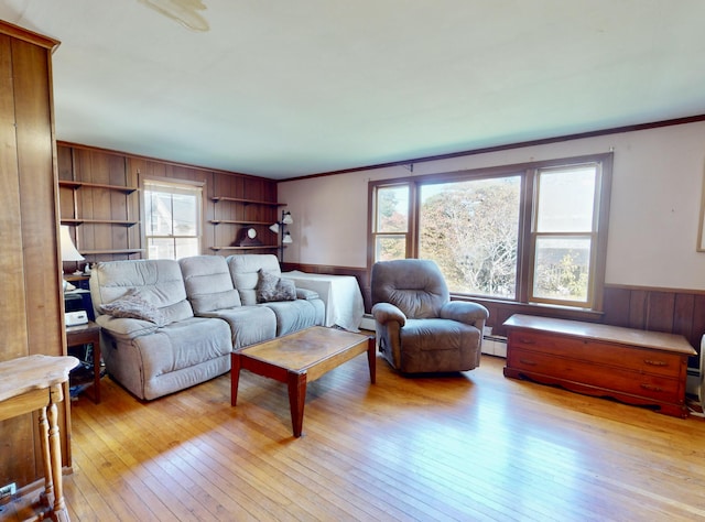 living room featuring ornamental molding, wood walls, a baseboard heating unit, wainscoting, and light wood finished floors