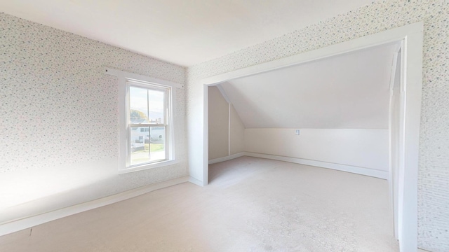 additional living space featuring wallpapered walls, baseboards, and vaulted ceiling