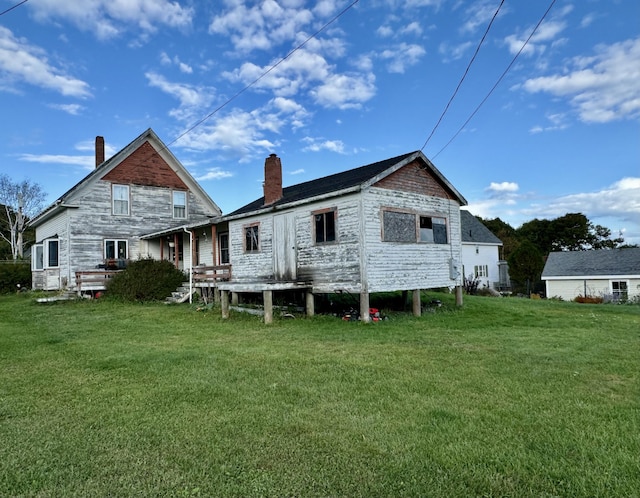 back of property featuring a chimney and a lawn