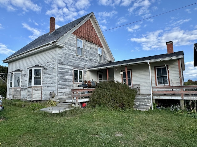 back of property with a deck, heating fuel, a lawn, and a chimney