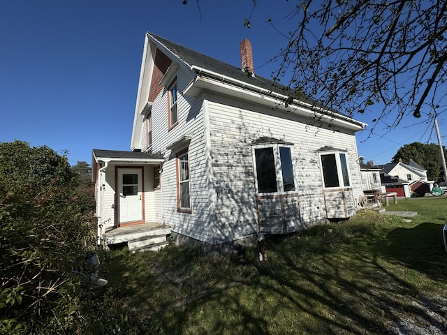 view of side of home featuring a chimney and a lawn