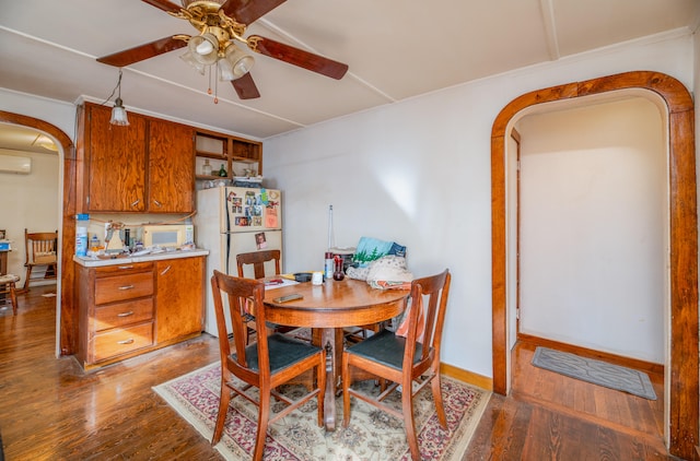 dining area featuring ceiling fan, ornamental molding, hardwood / wood-style floors, and a wall mounted AC