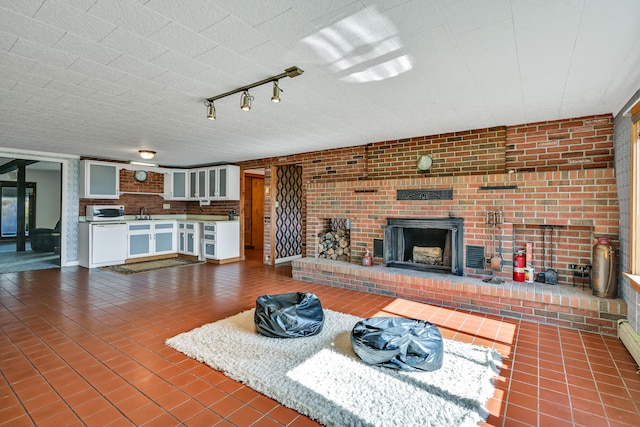 unfurnished living room featuring a fireplace, brick wall, tile patterned floors, and sink