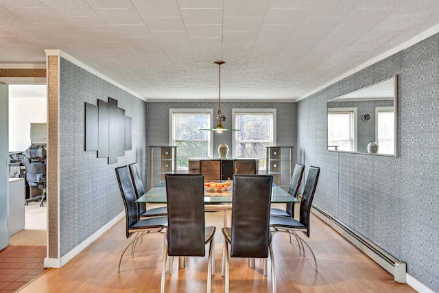 dining room with wood-type flooring, crown molding, and a baseboard heating unit