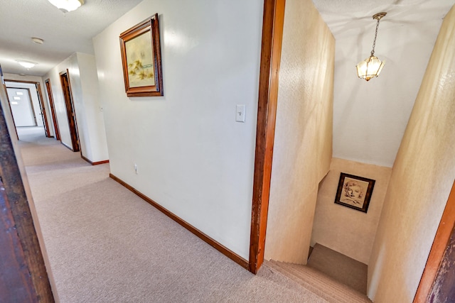 hallway with light colored carpet and a textured ceiling