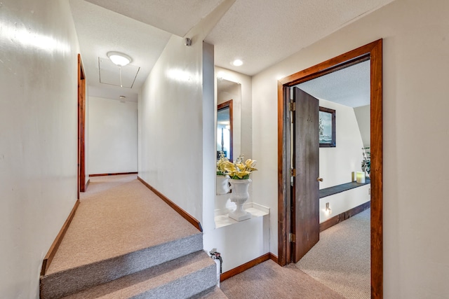 hall with a textured ceiling and light colored carpet