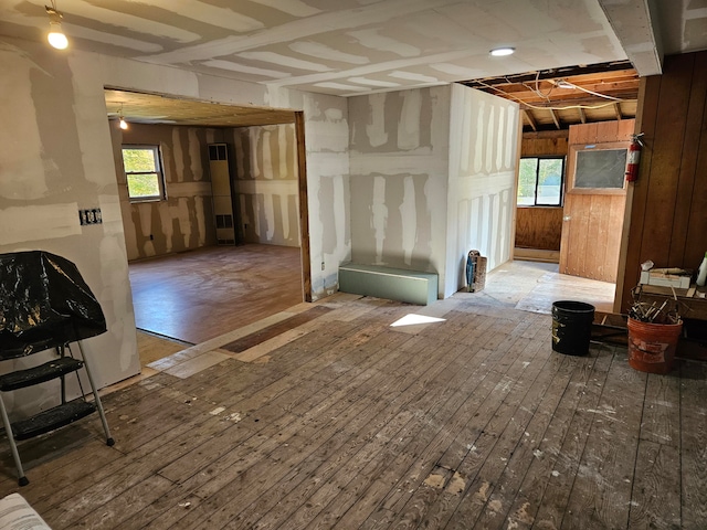 misc room with wood-type flooring, wooden walls, and plenty of natural light