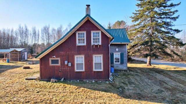 view of property exterior with a lawn and an outbuilding