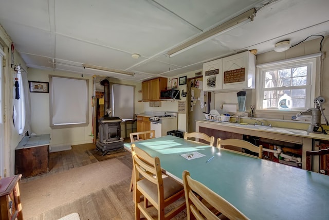 kitchen with light wood-type flooring, white gas range, and a wood stove