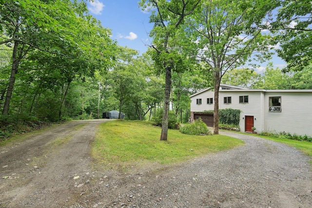 view of front facade with a front yard, dirt driveway, and an attached garage