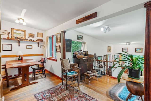 sitting room with baseboards, decorative columns, vaulted ceiling, and wood finished floors