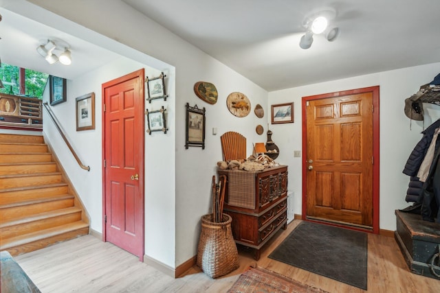 entrance foyer featuring stairs, baseboards, and wood finished floors