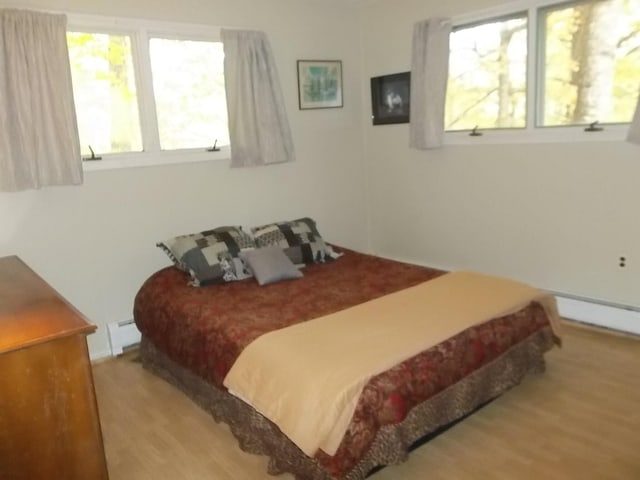 bedroom featuring hardwood / wood-style flooring and a baseboard heating unit