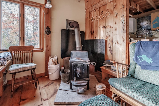 sitting room featuring hardwood / wood-style flooring, beam ceiling, and a wood stove