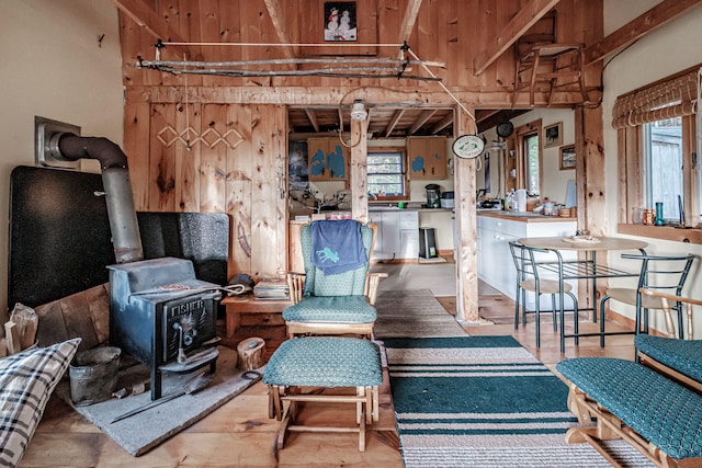 living room with a wood stove, beamed ceiling, and hardwood / wood-style floors