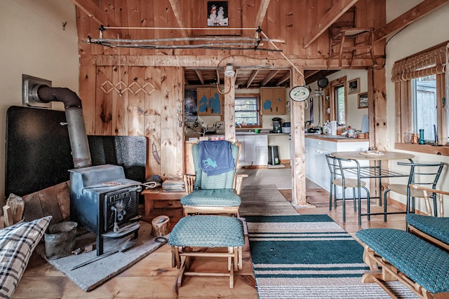 interior space with a wood stove, beam ceiling, and wood finished floors