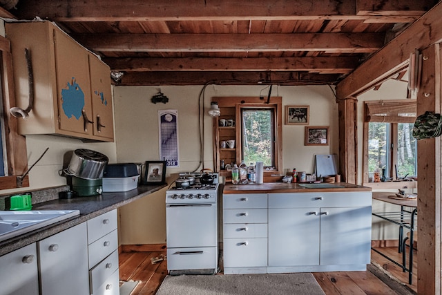 kitchen featuring beamed ceiling, light hardwood / wood-style floors, white range with gas cooktop, and a healthy amount of sunlight