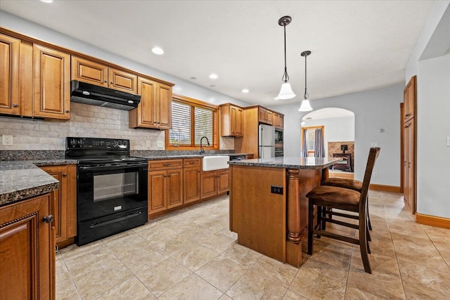 kitchen featuring a kitchen island, a breakfast bar area, hanging light fixtures, black range with electric stovetop, and stainless steel refrigerator