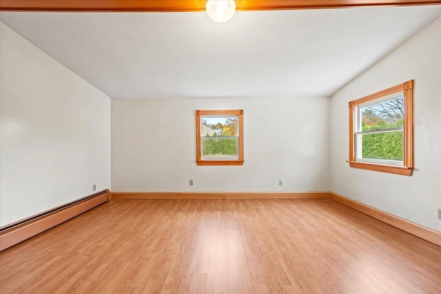 empty room featuring light hardwood / wood-style floors, a textured ceiling, and baseboard heating