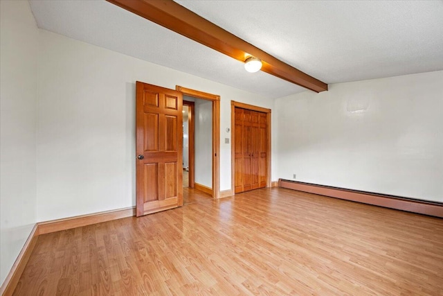 spare room with baseboard heating, beam ceiling, a textured ceiling, and light wood-type flooring