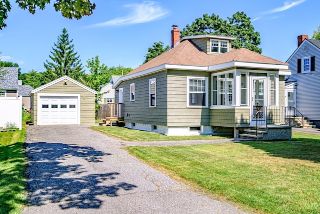 view of front facade with a front yard, a garage, and an outbuilding