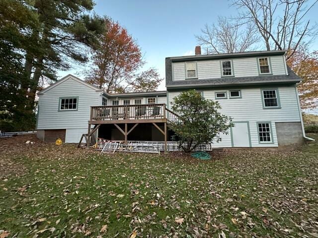 rear view of property featuring a deck and a lawn