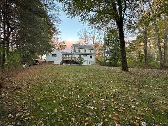 back house at dusk featuring a yard and a wooden deck